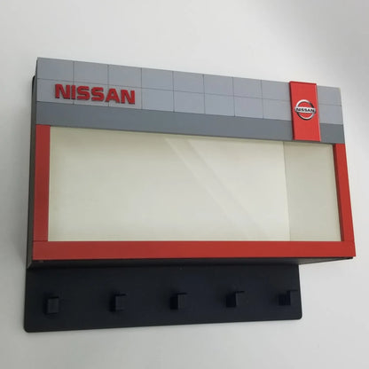 Gray and red Nissan-branded wall key hook rack with five black hooks and clear display case.
