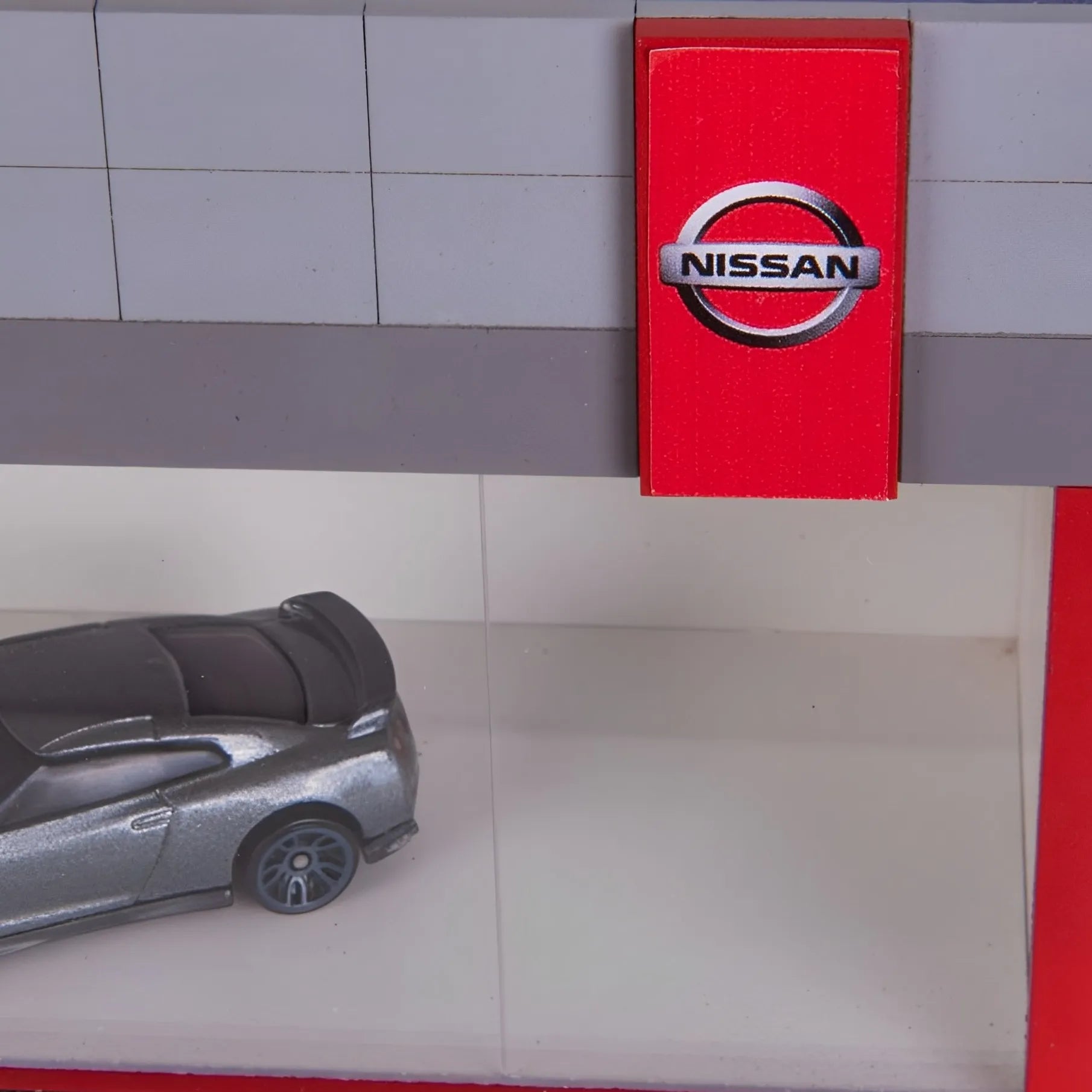 Red rectangular Nissan wall key hook rack with white Nissan logo and silver key hooks inside.