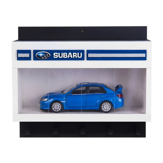 White rectangular wall key hook rack with Subaru logo and blue scale model car displayed inside transparent case.
