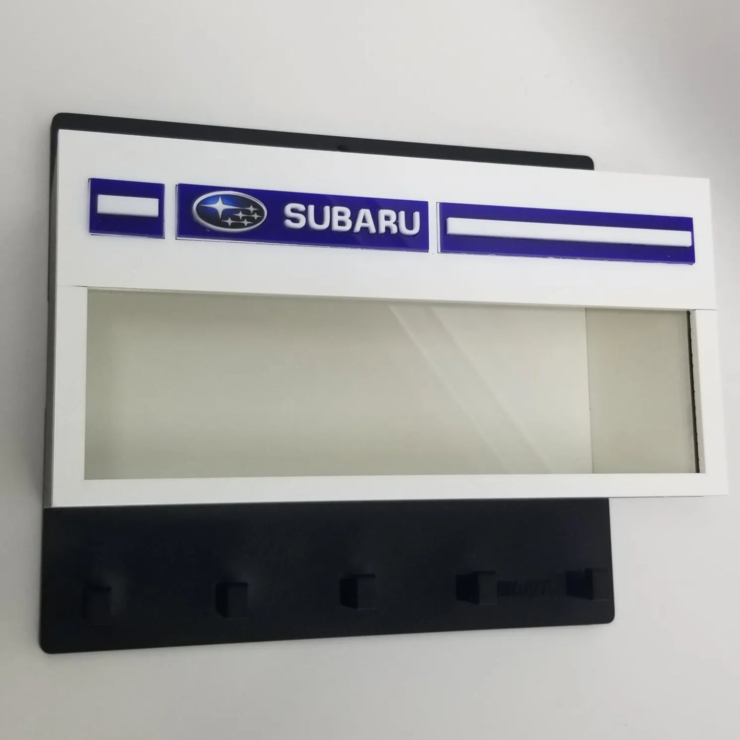 Black and white Subaru wall key hook rack with clear display case and four hooks.