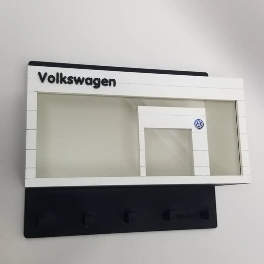 Volkswagen-themed white wall key hook rack with black base and clear display case resembling a car showroom facade.