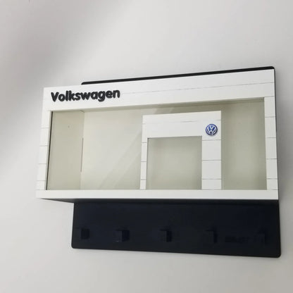 White Volkswagen-themed wall key hook rack with four black hooks and a scale model car display case design.