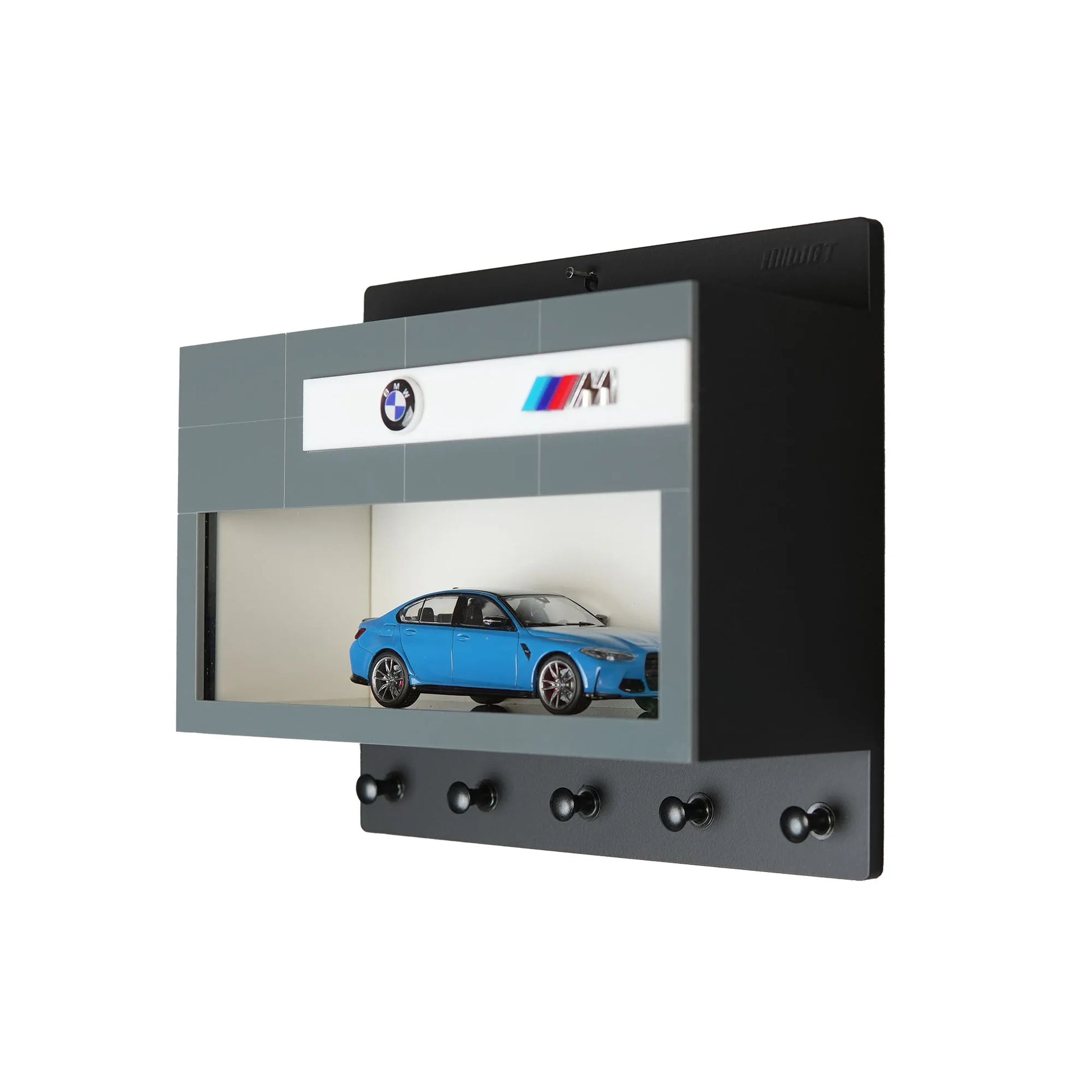 Black and gray wall-mounted key hook rack with five hooks and a blue BMW M scale model car displayed inside a clear-front.