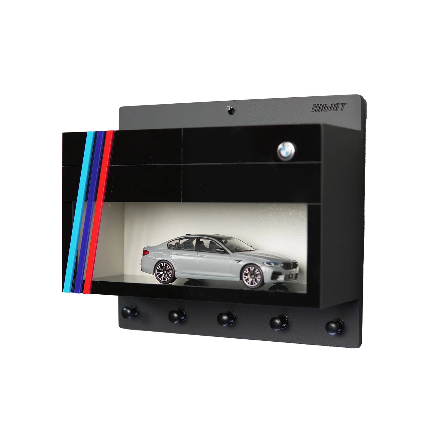 Black wall-mounted key rack with four BMW logo hooks, built-in display case featuring silver BMW scale model, and decorative