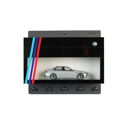 Black BMW wall-mounted key hook rack with red, blue, and light blue stripes and silver scale model car display case.