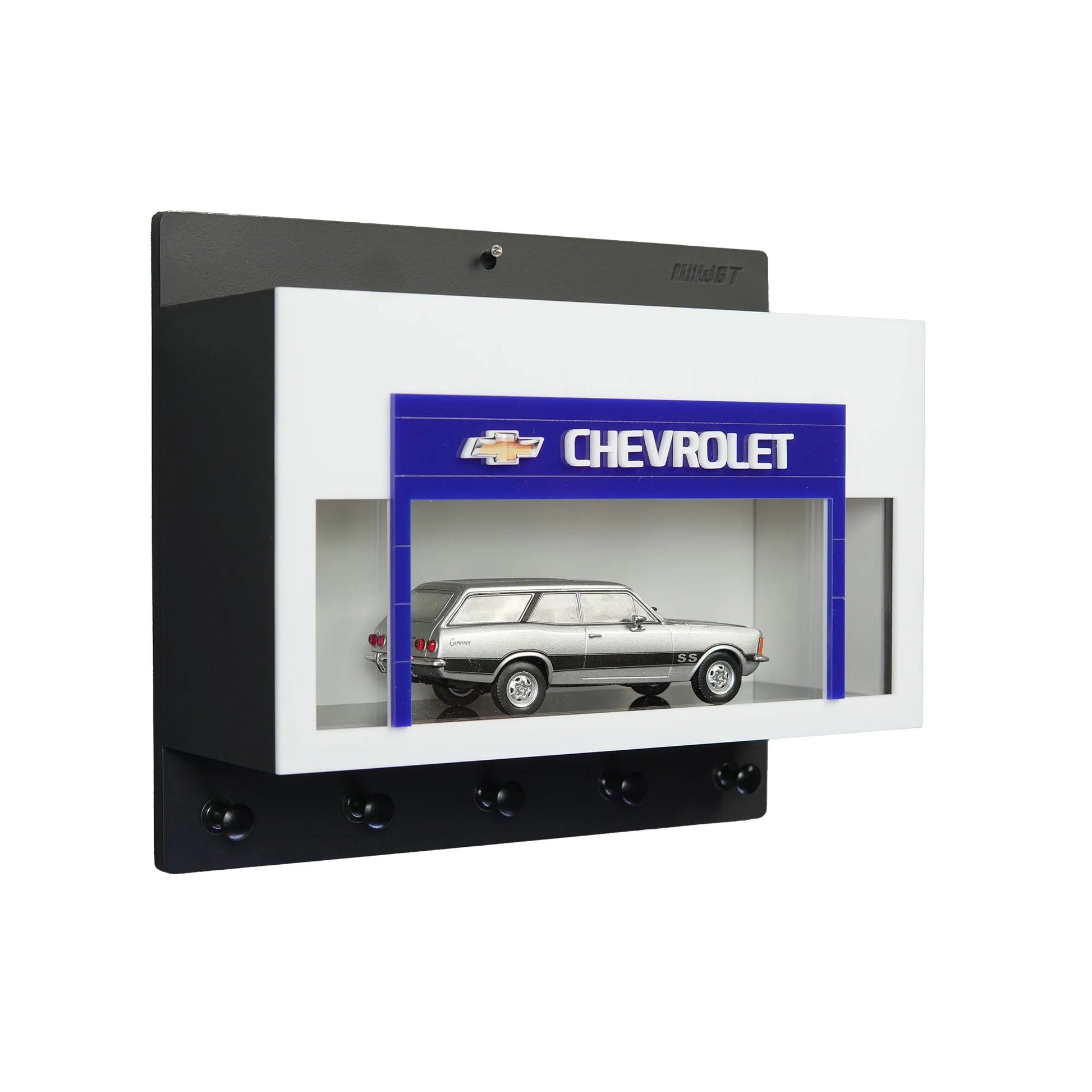 Black and white wall-mounted key hook rack with Chevrolet logo and silver scale model car display case.