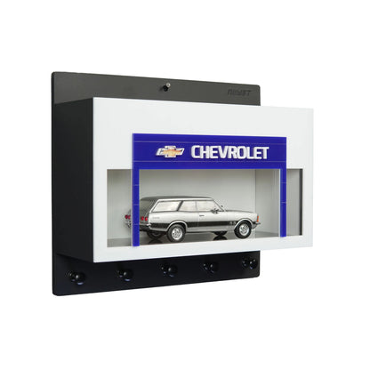 Black and white wall-mounted key hook rack with Chevrolet logo and silver scale model car display case.