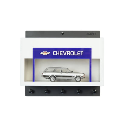 White wall key hook rack with a built-in display case featuring a silver scale model Chevrolet station wagon and five black.