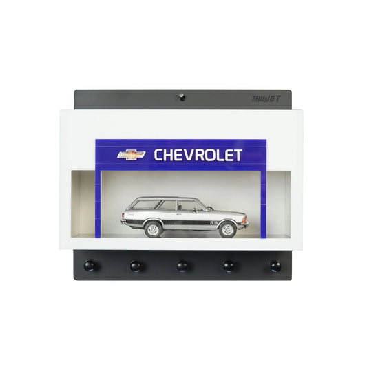 White wall key hook rack with a built-in display case featuring a silver scale model Chevrolet station wagon and five black.