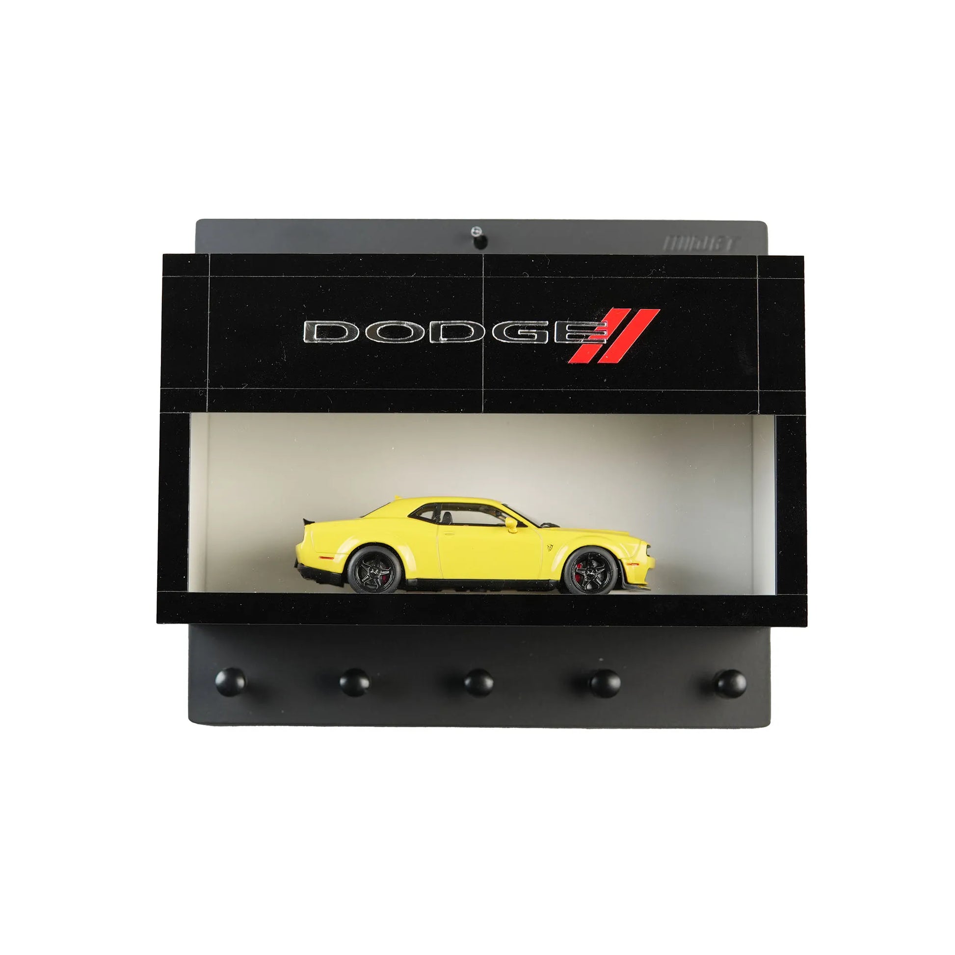 Black wall-mounted key hook rack with Dodge logo and a yellow scale model car display shelf.