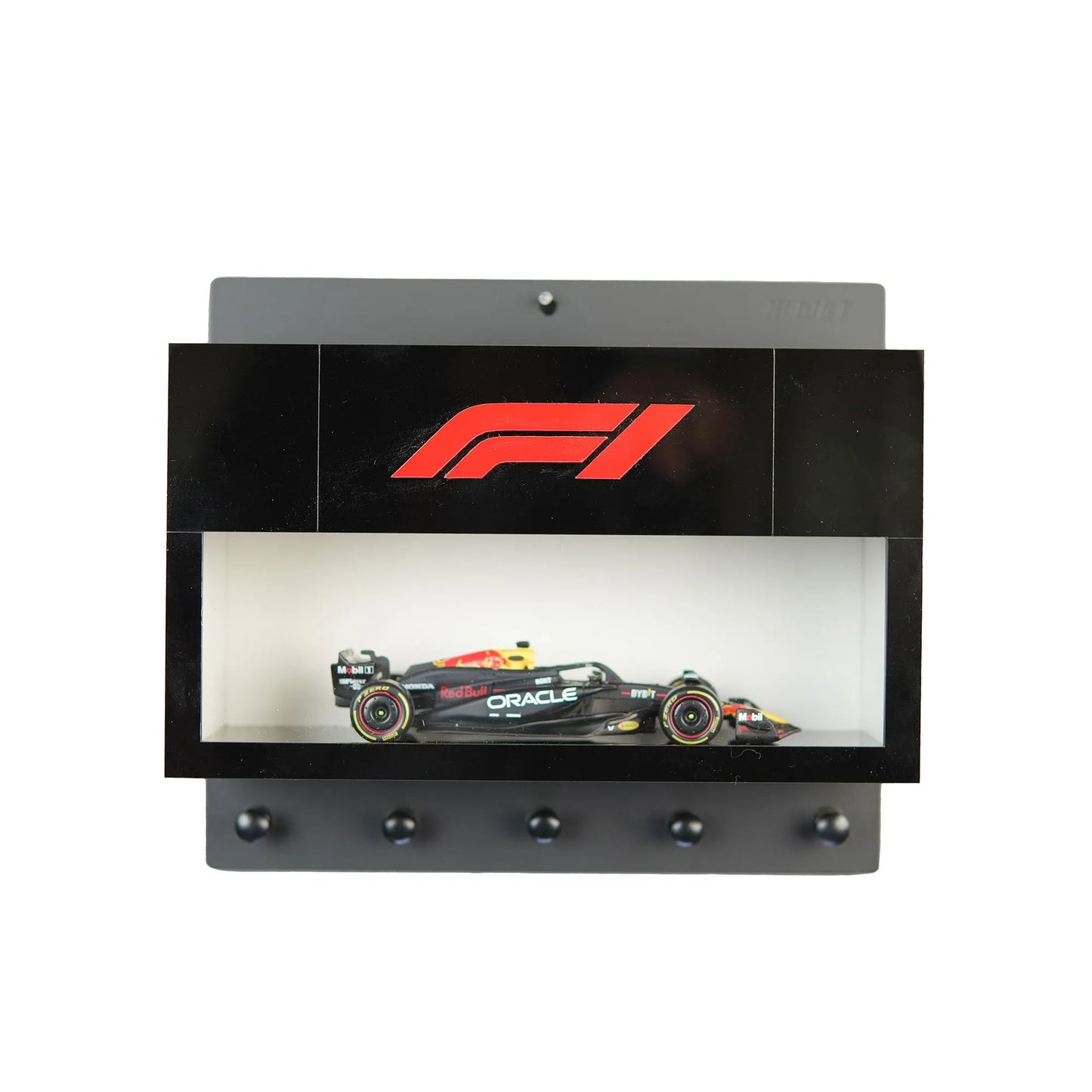Black wall-mounted key hook rack with F1 logo and a scale model Formula One car in a display case.