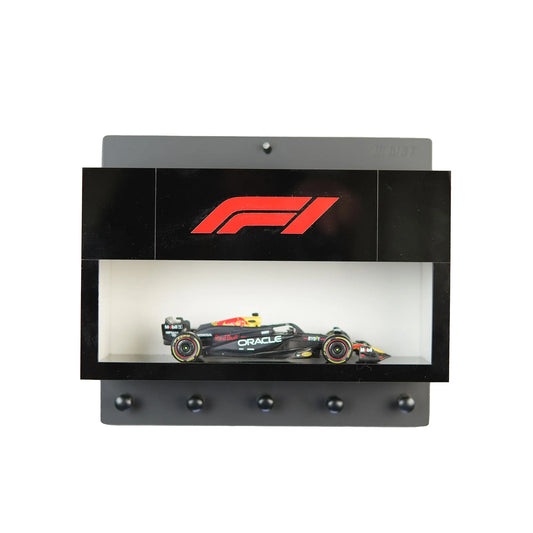 Black wall-mounted key hook rack with F1 logo and a scale model Formula One car in a display case.