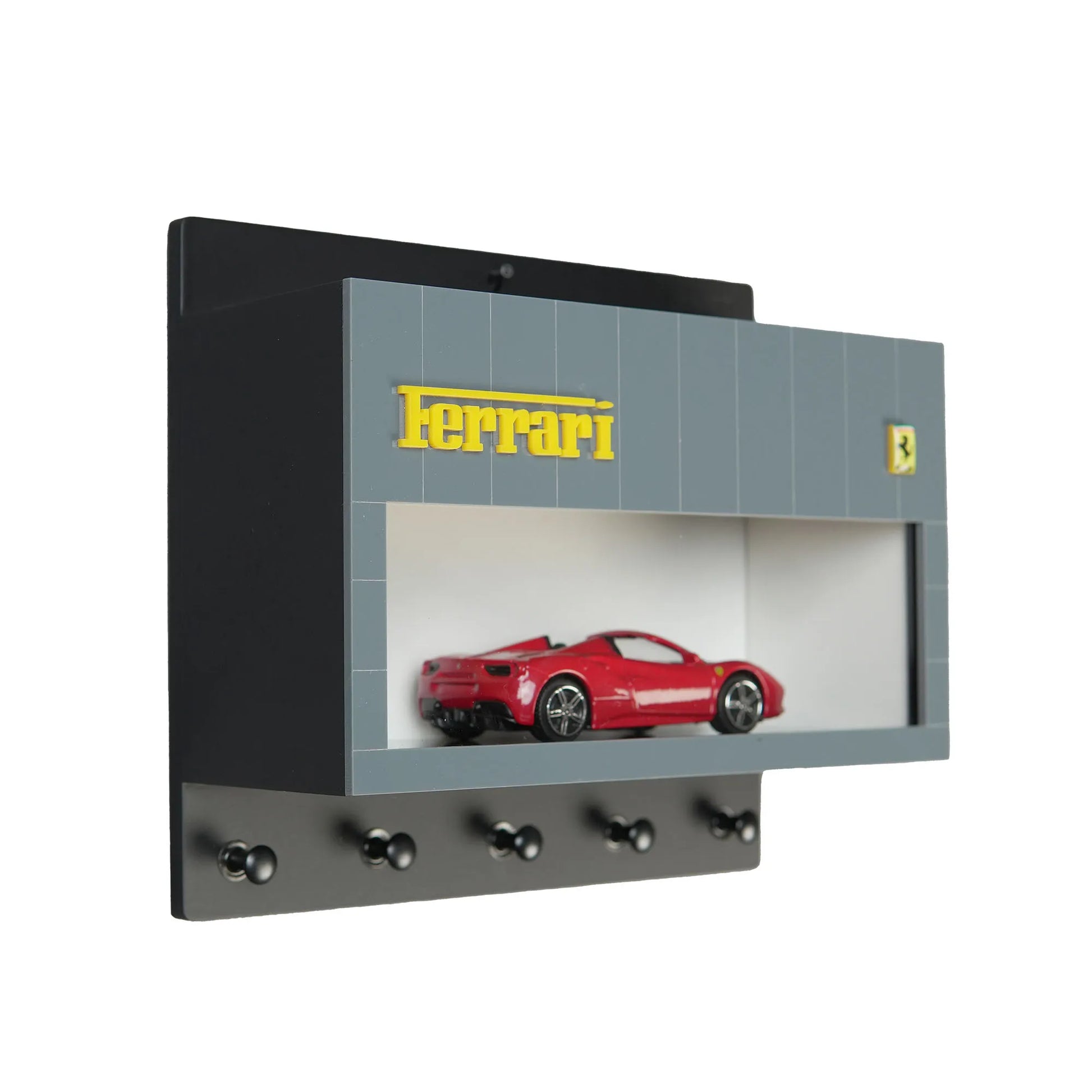 Gray wall-mounted key hook rack with Ferrari logo and red model car display case.