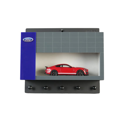 Wall-mounted key hook rack designed as a Ford garage with a red scale model car inside and four black hooks below.