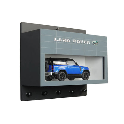 Black wall-mounted key hook rack featuring a blue Land Rover scale model inside a rectangular display case with Land Rover.
