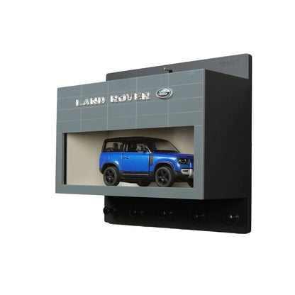 Black and gray Land Rover wall key hook rack with a blue scale model SUV display case.