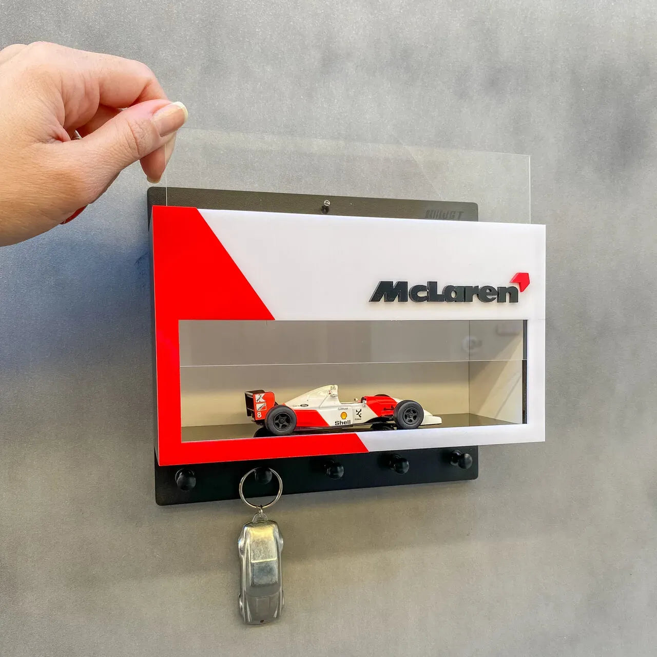 McLaren vintage F1 car model displayed in white and red wall-mounted key hook rack with three black hooks.