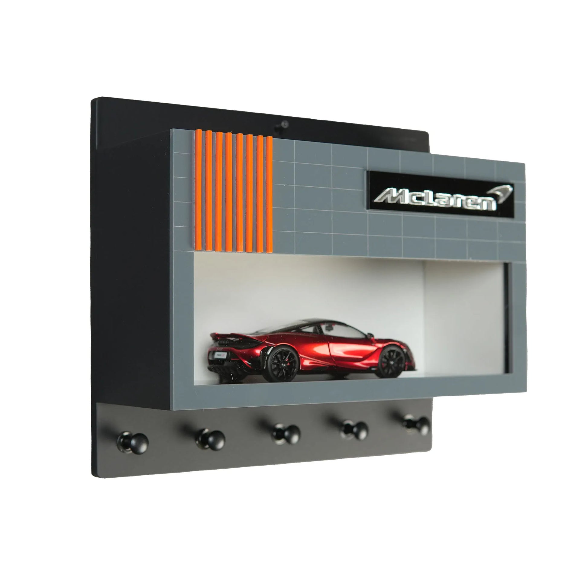 Black wall key hook rack with five hooks and a red McLaren model car display case with gray and orange detailing.