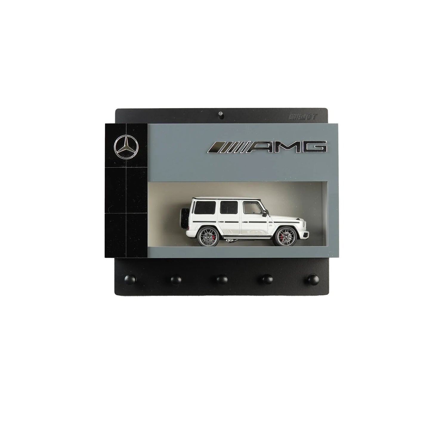 Black and gray Mercedes AMG wall key hook rack with white scale model G-Class SUV and four hooks.