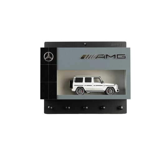 Black and gray Mercedes AMG wall key hook rack with white scale model G-Class SUV and four hooks.