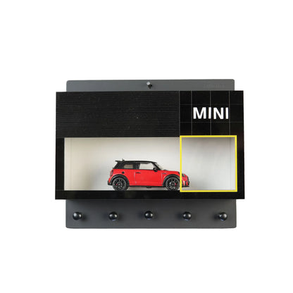 Black wall-mounted key rack with five hooks and built-in display case holding a red Mini Cooper model car.