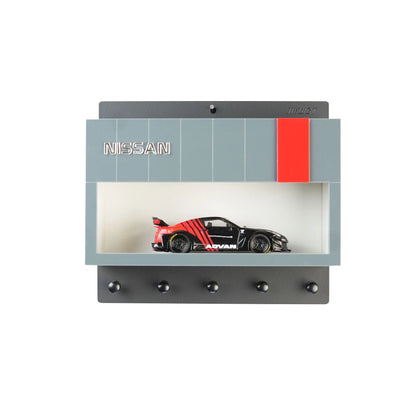 Gray and red Nissan-themed wall key hook rack with scale model car displayed inside.