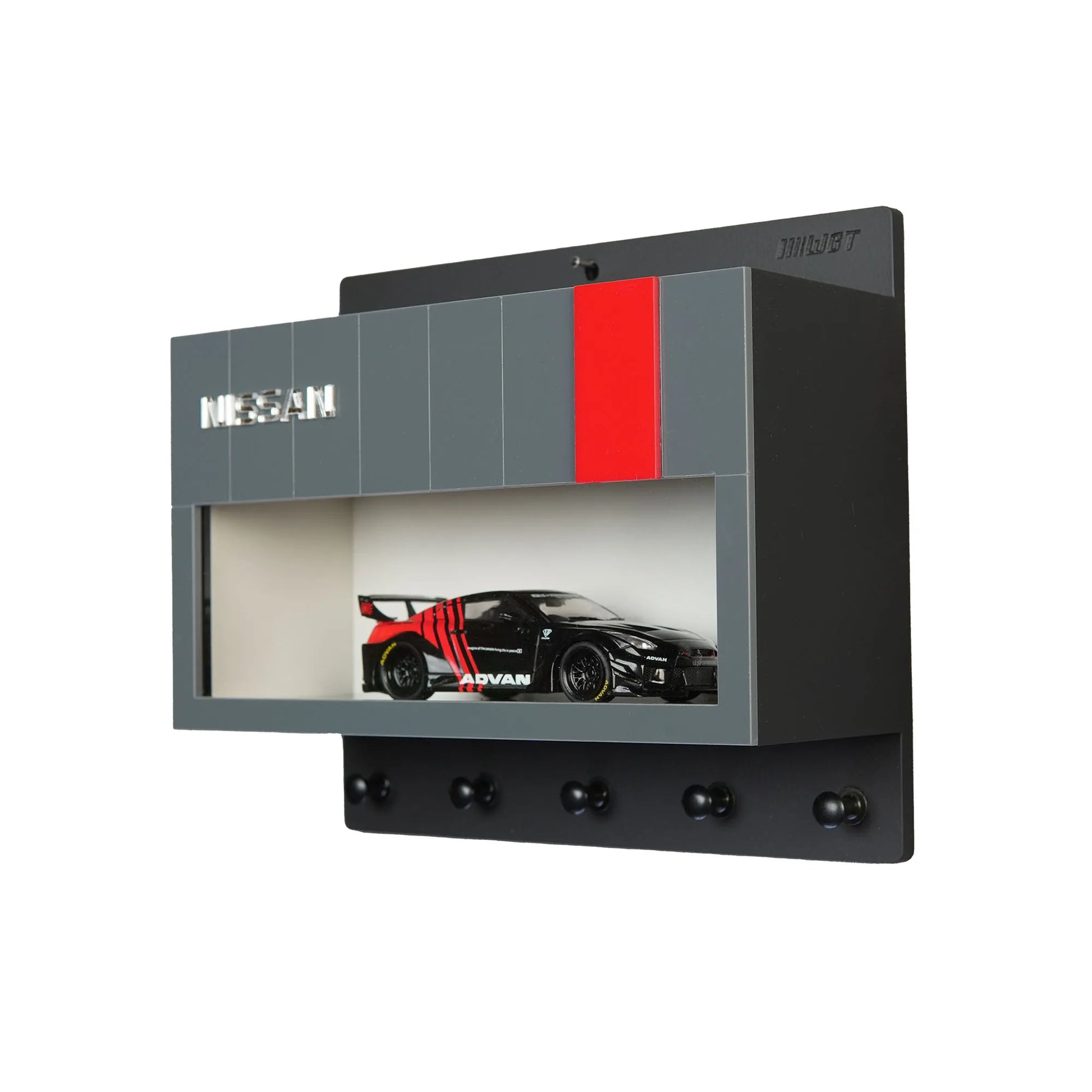 Black and gray Nissan wall key hook rack with a scale model black and red race car in a display case and four hooks below.