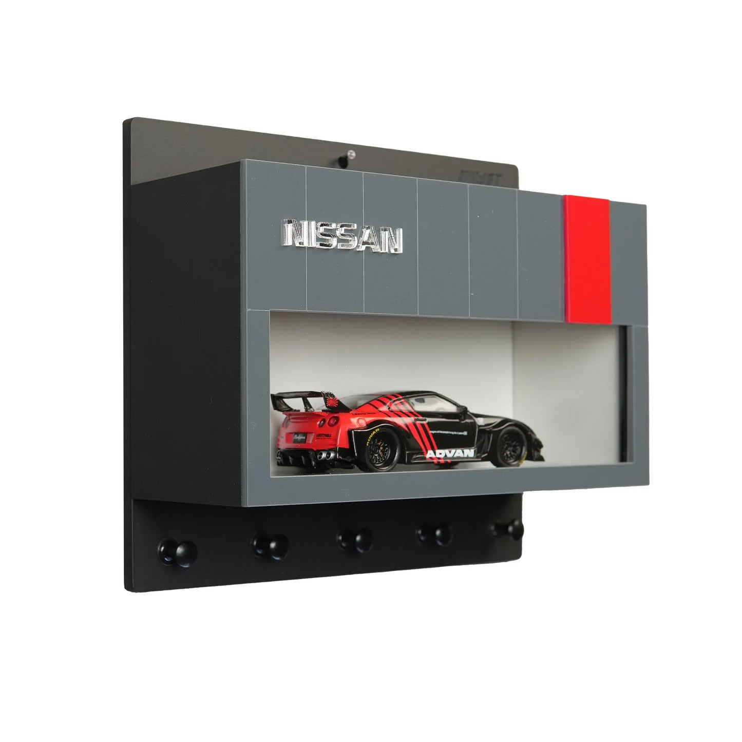 Black and gray Nissan wall key hook rack with red accent and scale model car display shelf.