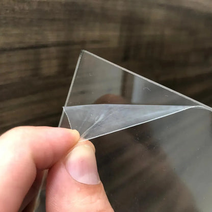 Clear flexible plastic sheet held at the corner, showing thin, transparent material texture.